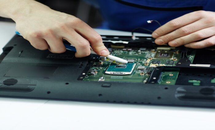 Laptop repair technician offering assistance over phone while fixing a laptop at a service center.